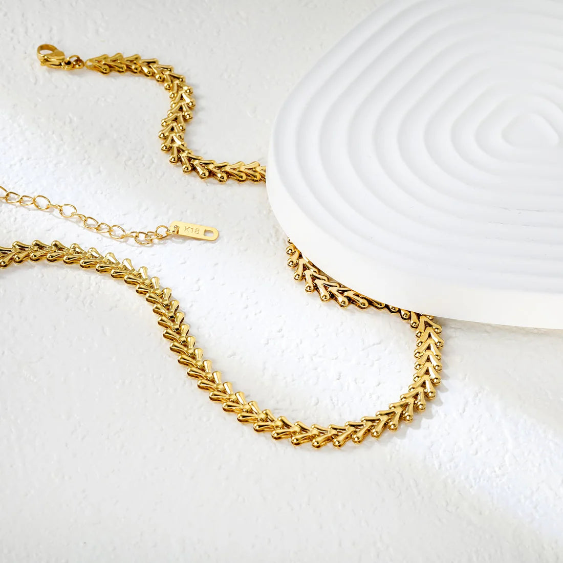 Gold chain necklace on a white textured surface