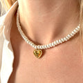 Pearl necklace with a gold heart pendant worn by a person