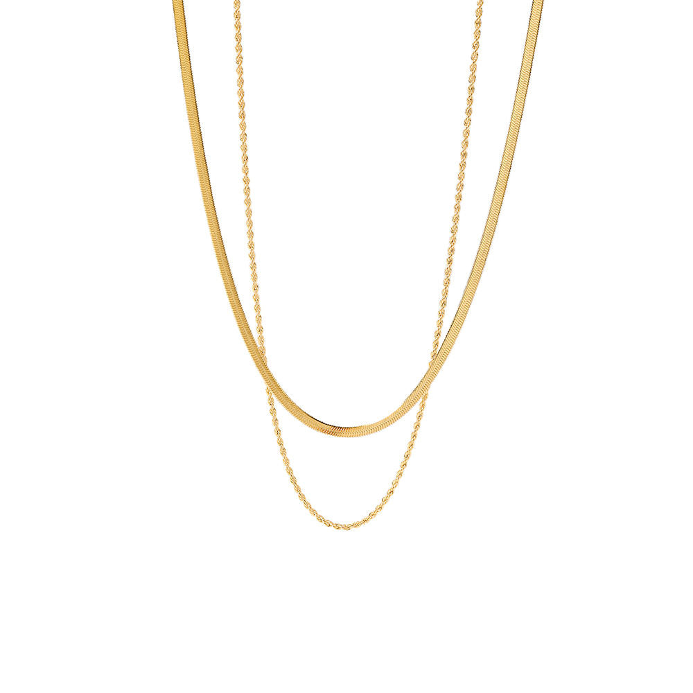 Layered gold herringbone and rope necklaces on a white background. Stainless steel jewelry, gold simple chains