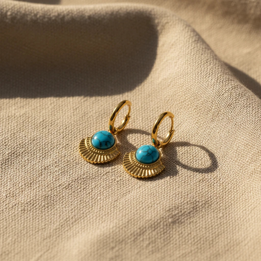 Gold hoop earrings with turquoise stones on a white surface