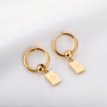 Gold hoop earrings with rectangular charms on a light gray background