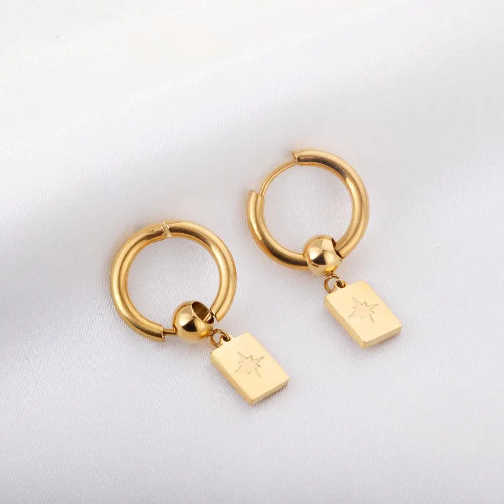 Gold hoop earrings with rectangular charms on a light gray background