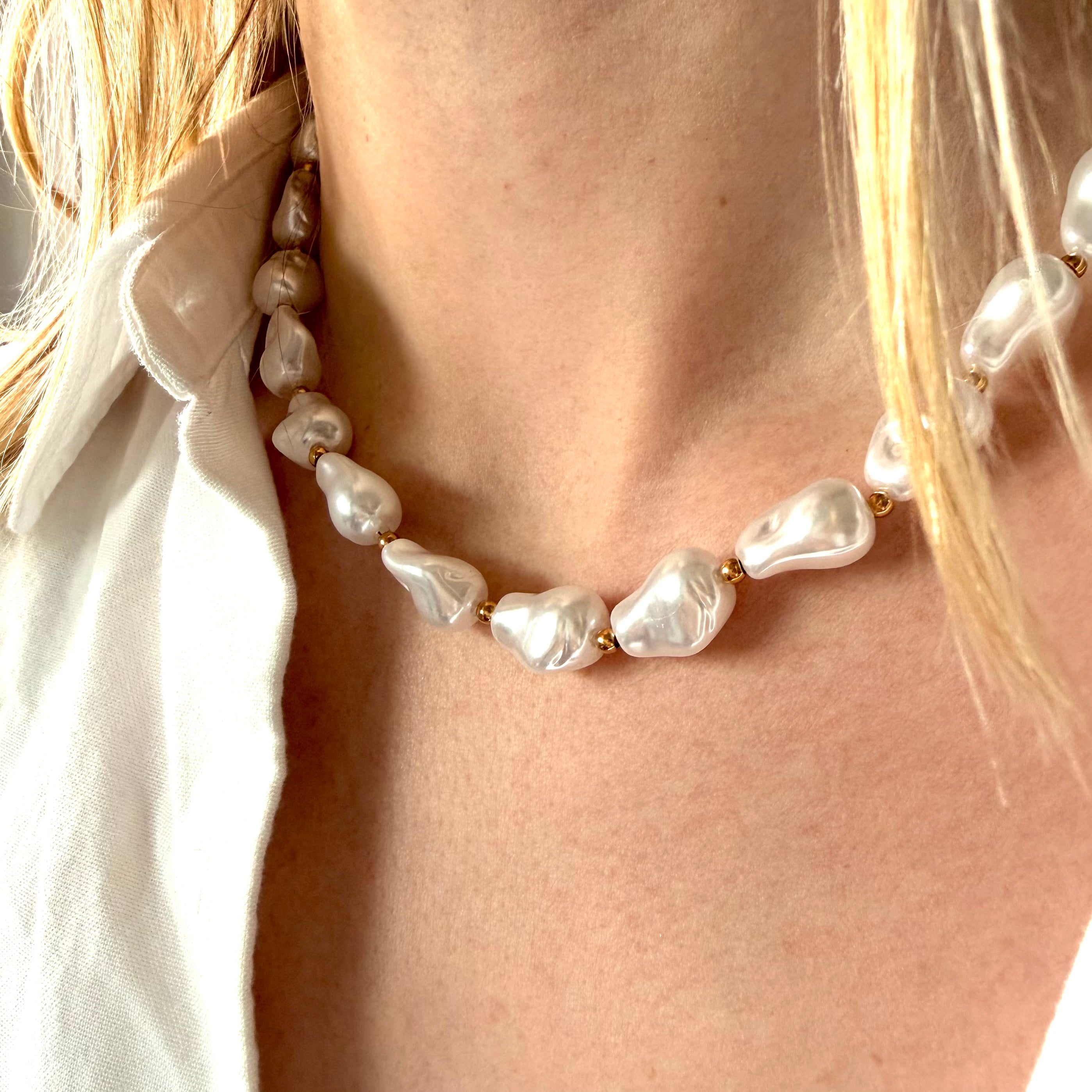 Pearl necklace worn by a person with a blurred background. chunky pearl necklace gold, toggle clasp necklace, statement pearl necklace
