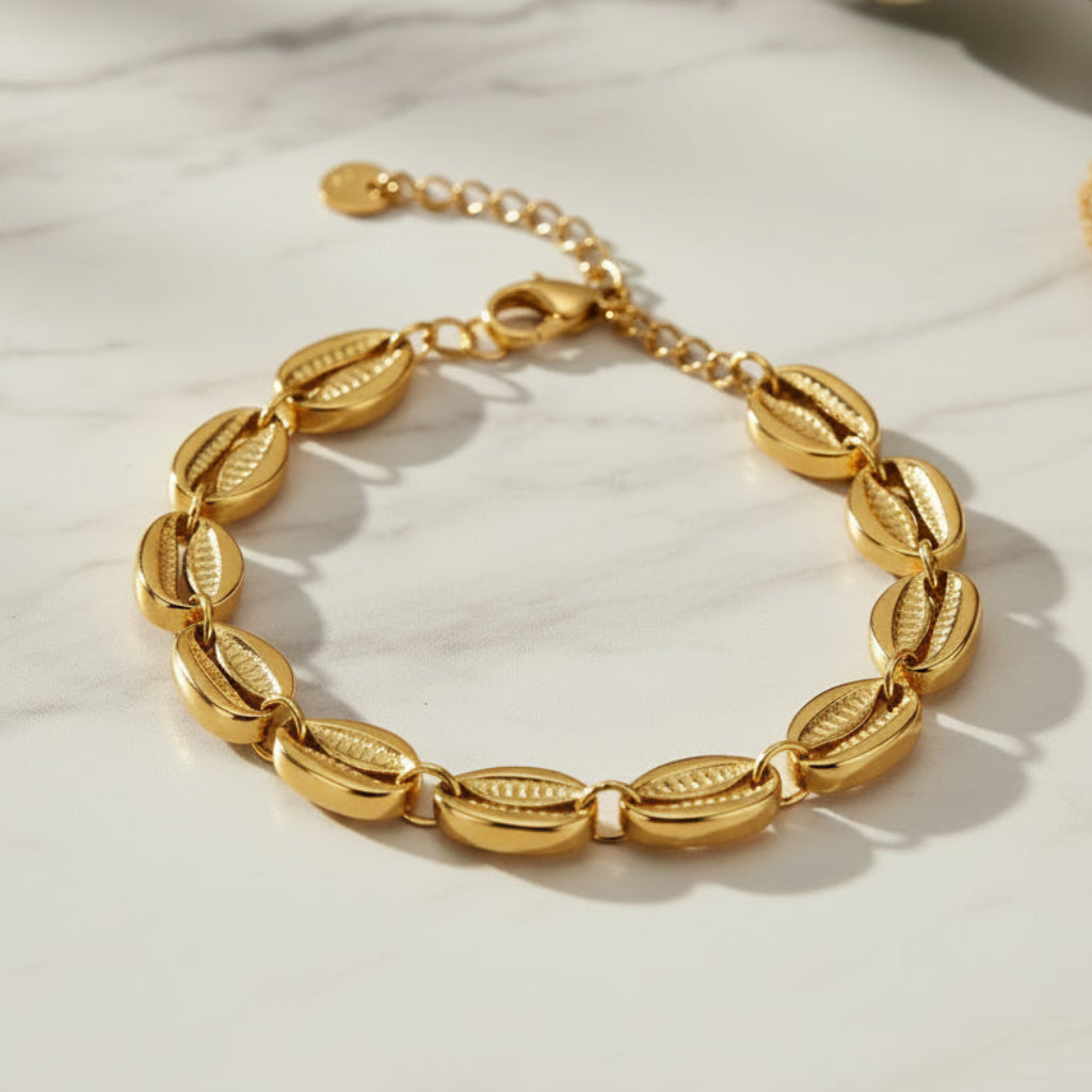 Gold bracelet with shell-like links on a white background. Beach inspired jewelry