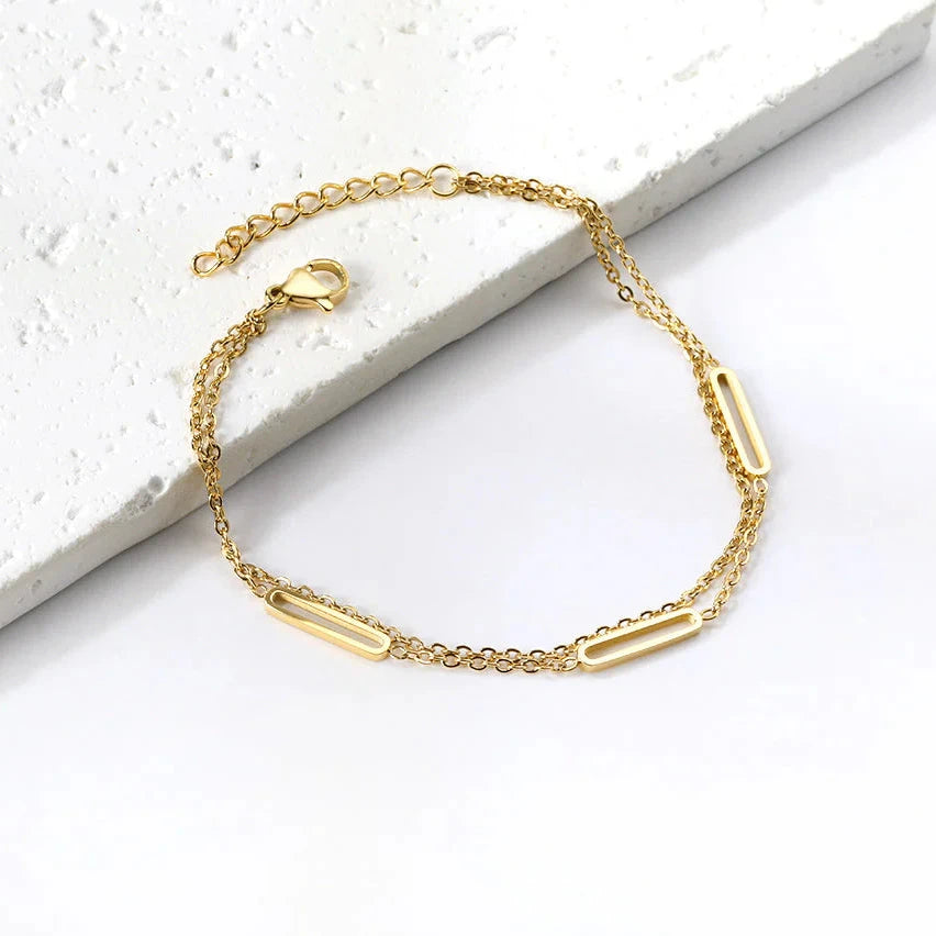 Gold double chain bracelet on a white stone surface. double chain bracelet gold, layered chain bracelet, oblong link bracelet