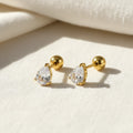 Gold stud earrings with teardrop zirconia gemstones on a white surface. teardrop zirconia stud earrings, gold stud earrings, dainty gold earrings