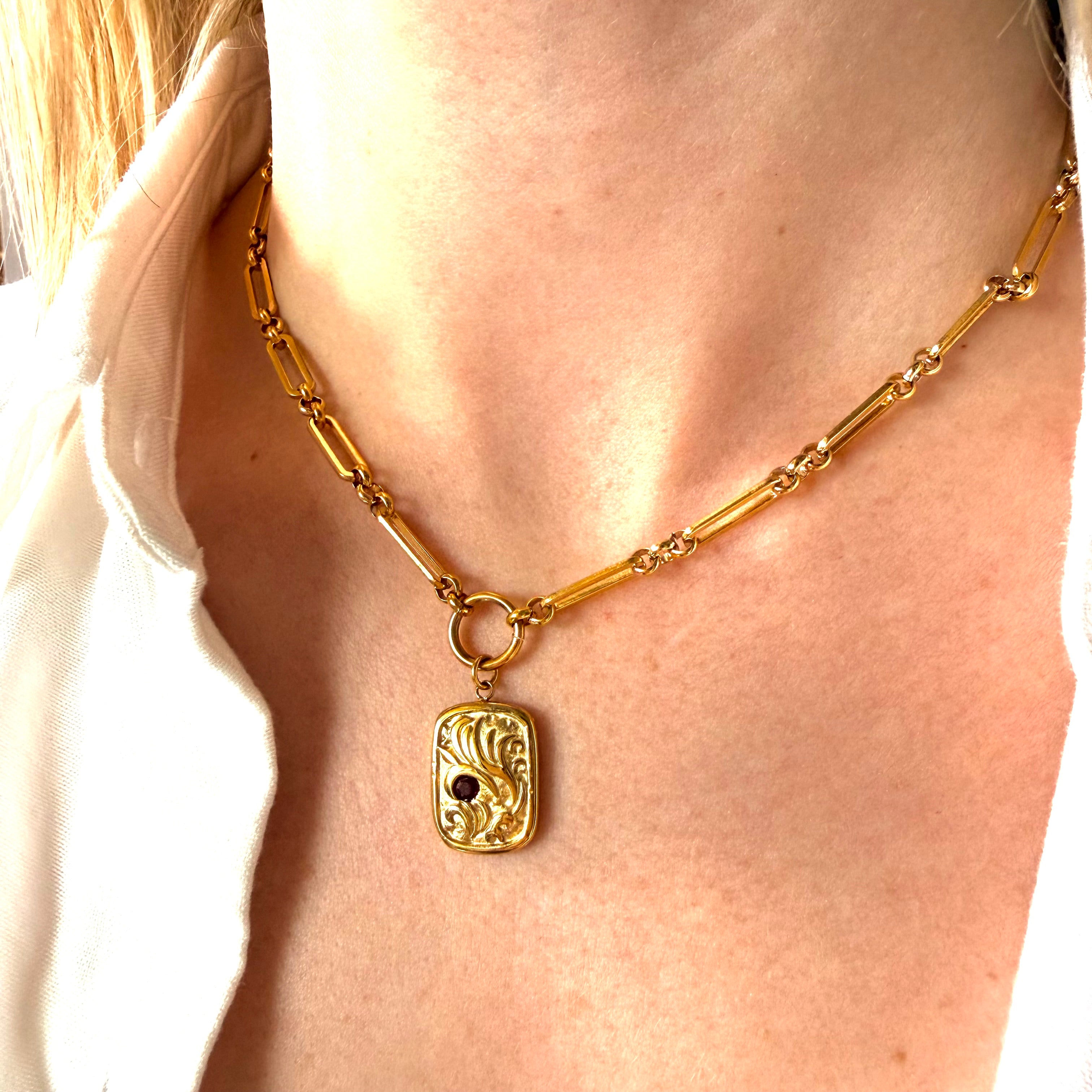 Gold necklace with a gold rectangular coin pendant on a person wearing a white shirt. gold coin necklace, ancient coin pendant, vintage style necklace
