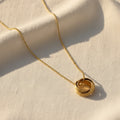 Gold necklace with a circular pendant on a white surface. Multi circle necklace gold, layered circle pendant necklace, minimalist gold necklace