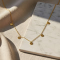 Gold necklace with round pendants on a white background