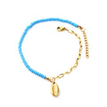 Anklet with conch shell charm and blue beads and gold chain on a white background. Beach jewelry, stainless steel jewelry