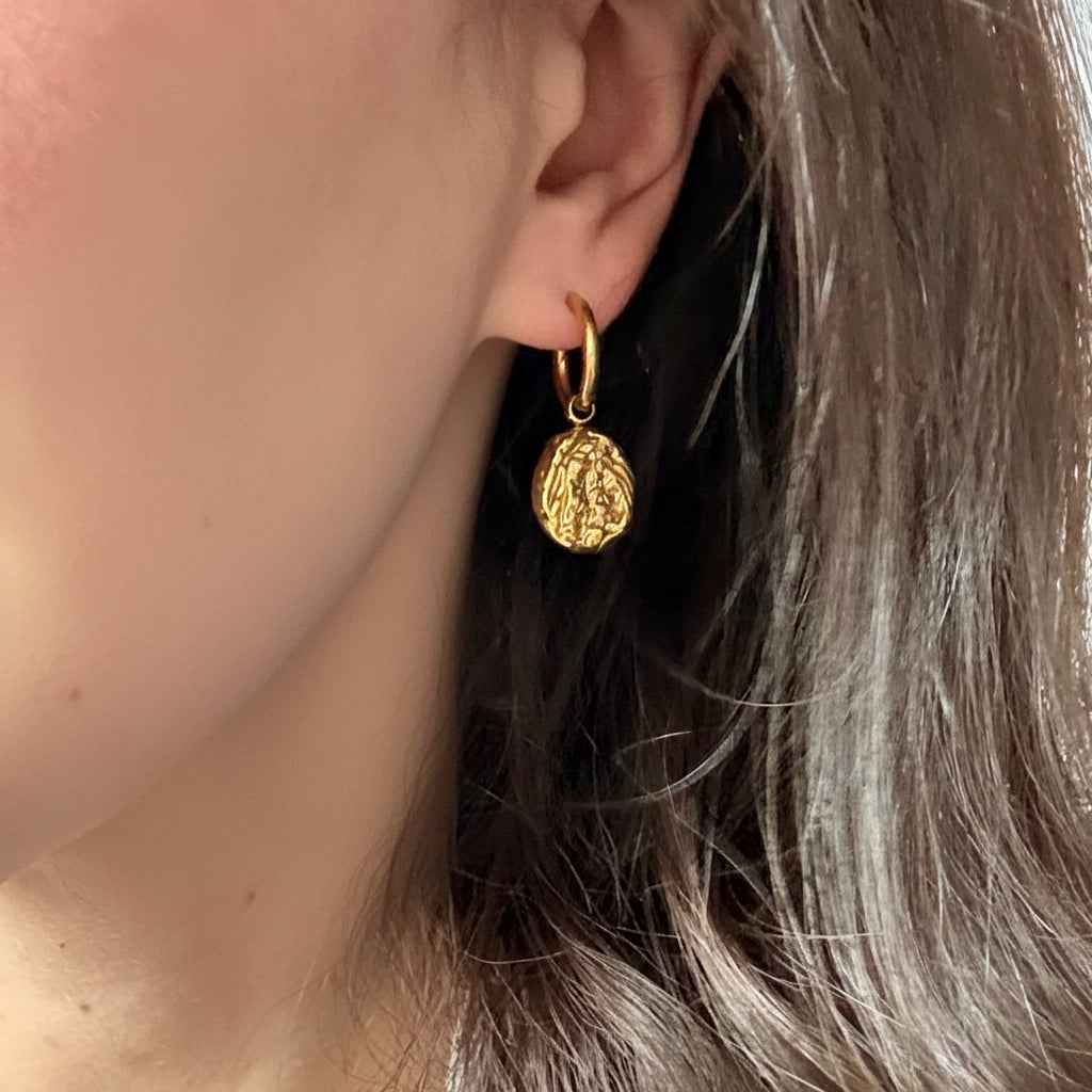 Close-up of a person wearing a gold drop earring. gold drop earrings, vintage style earrings, statement drop earrings