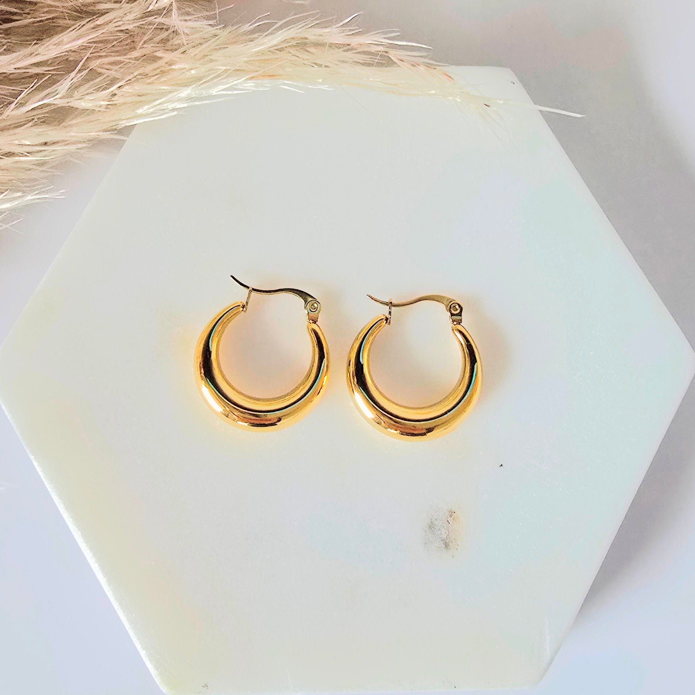 Gold hoop earrings on a white marblebackground