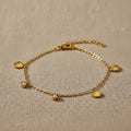 Gold bracelet with shell and zirconia charms on a white background
