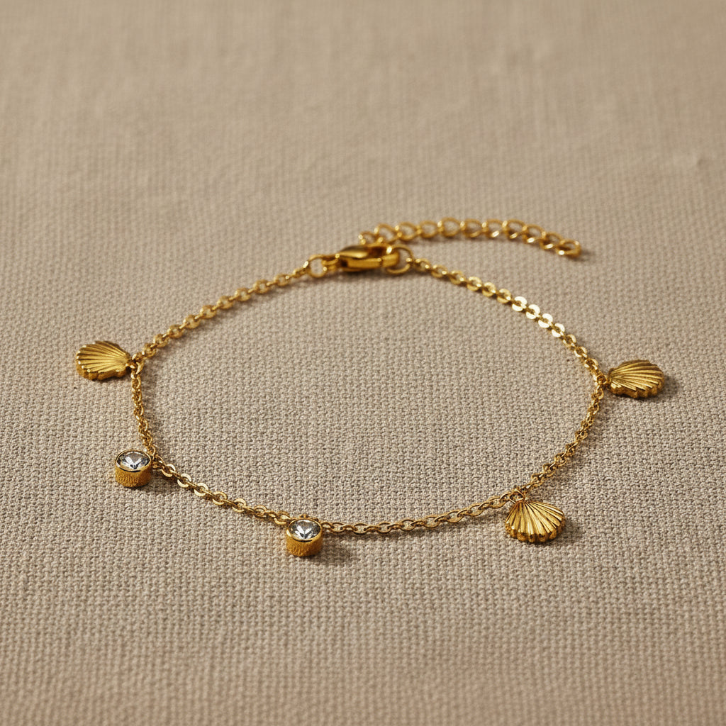 Gold bracelet with shell and zirconia charms on a white background