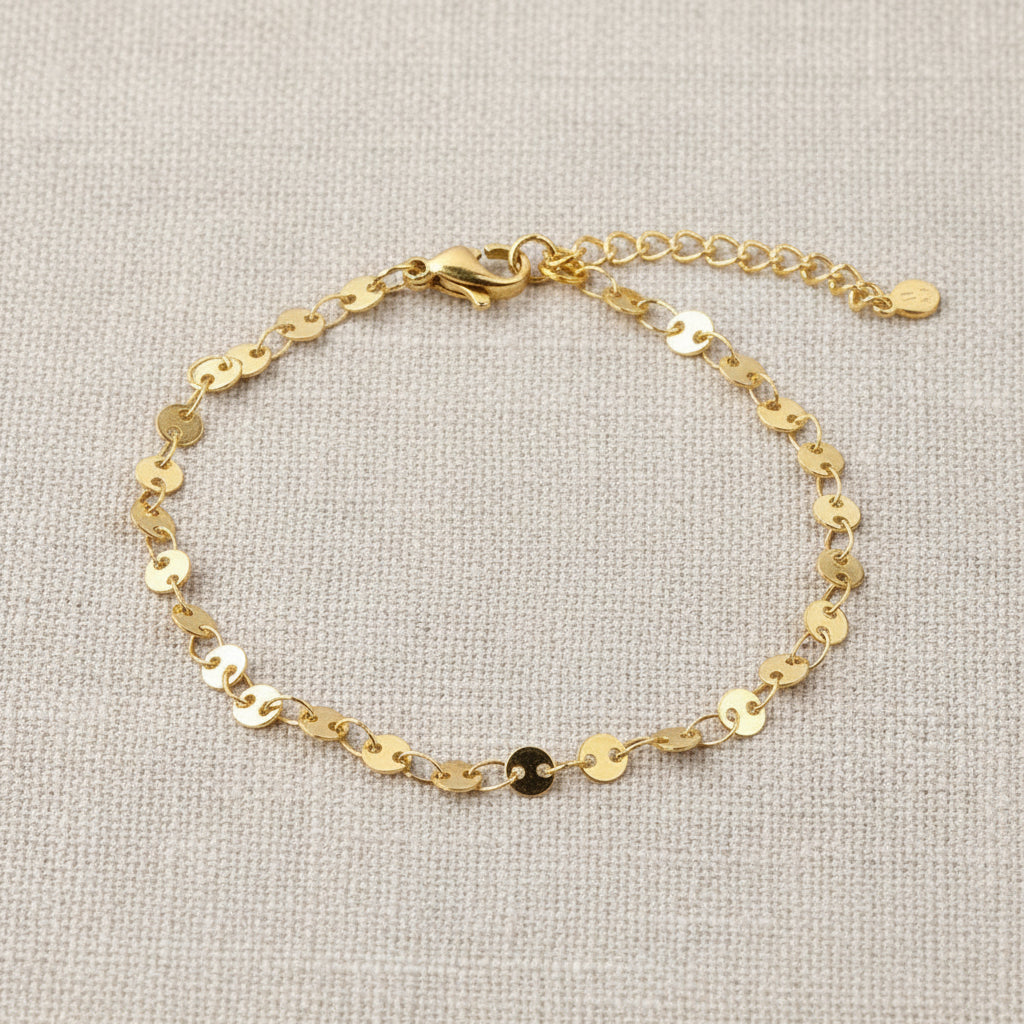 Gold disk bracelet on a white surface with wheat stalks