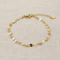Gold disk bracelet on a white surface with wheat stalks