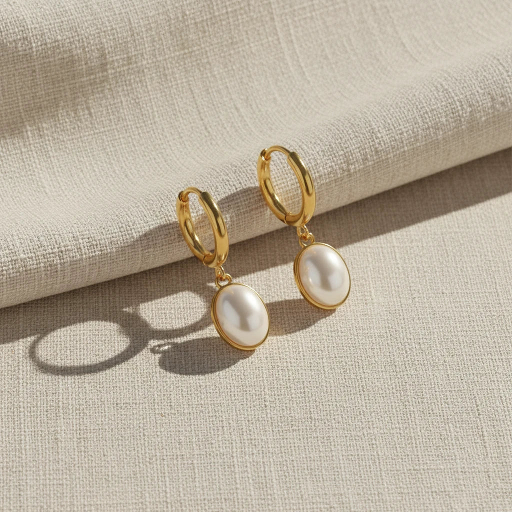 Gold hoop earrings with white pearl drops on a white background