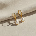 Gold hoop earrings with white pearl drops on a white background