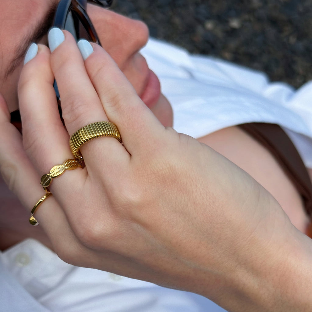 Close-up of a hand wearing gold rings with a blurred background