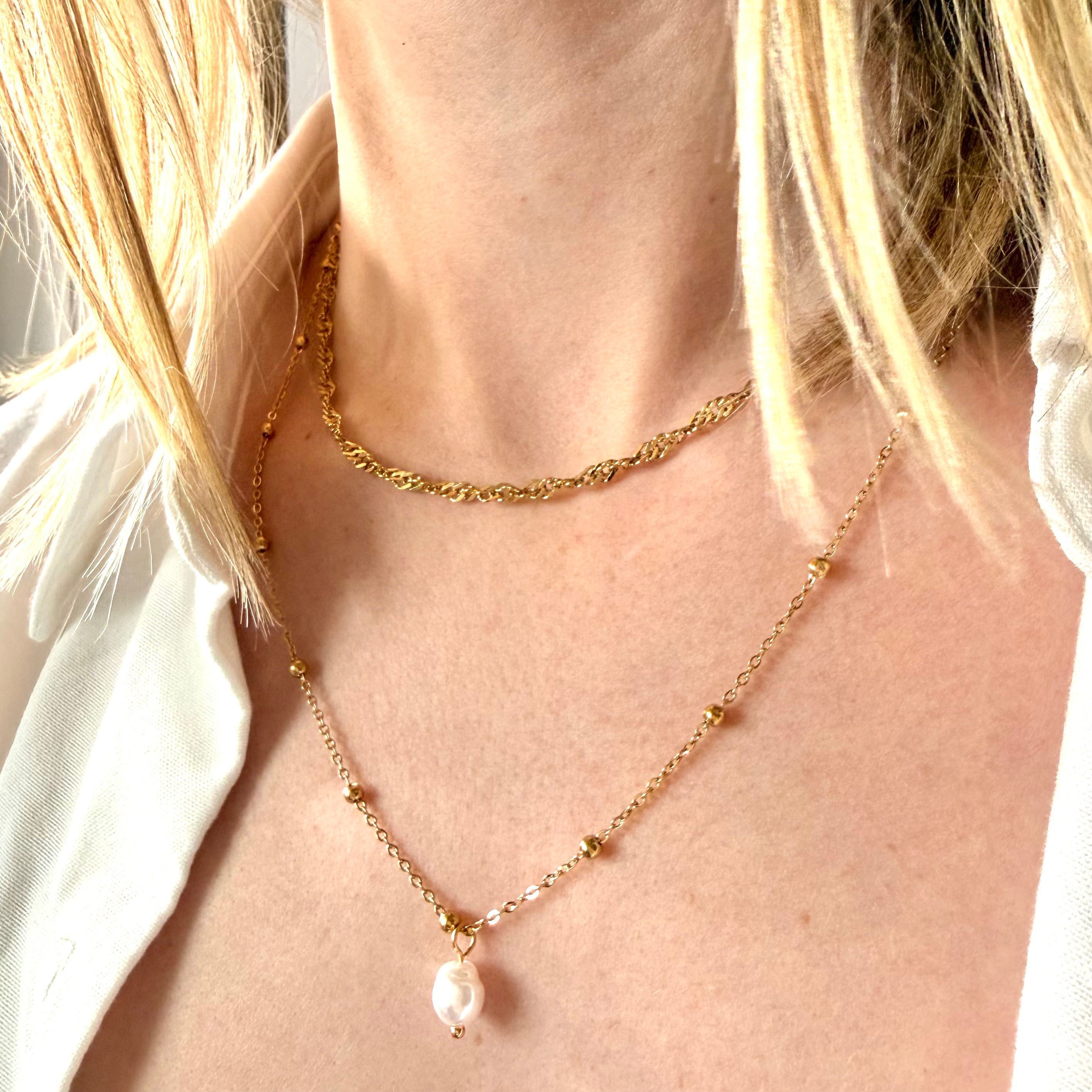 Gold necklace with a pearl pendant worn by a woman with blonde hair. double chain pearl necklace gold, layered pearl necklace, gold pearl pendant necklace