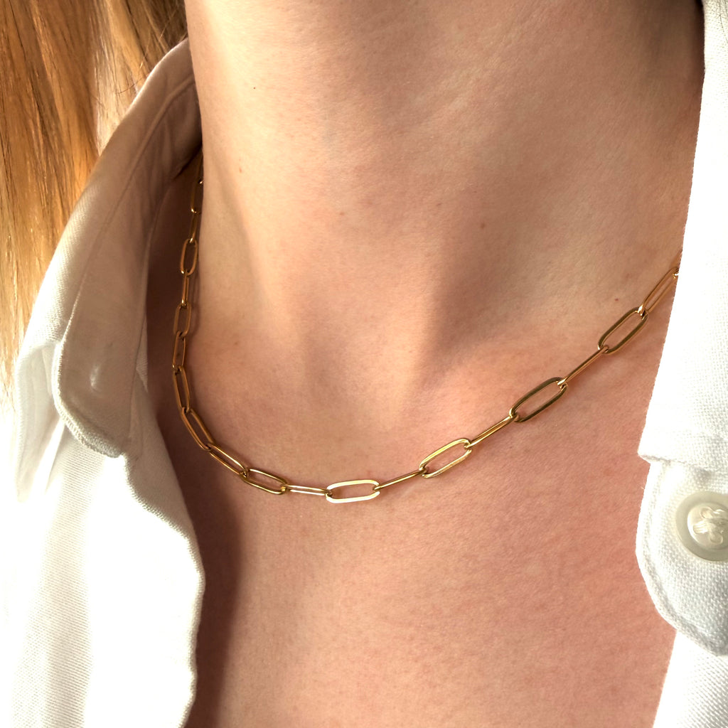 Gold chain paperclip necklace on a women's neck with white shirt