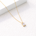 Gold necklace with a rectangular pendant on a textured white surface. rectangular zirconia necklace gold, crystal pendant necklace, minimalist gold necklace