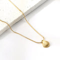 Gold necklace with a shell pendant on a white surface. Beach necklace. Ocean inspired jewelry