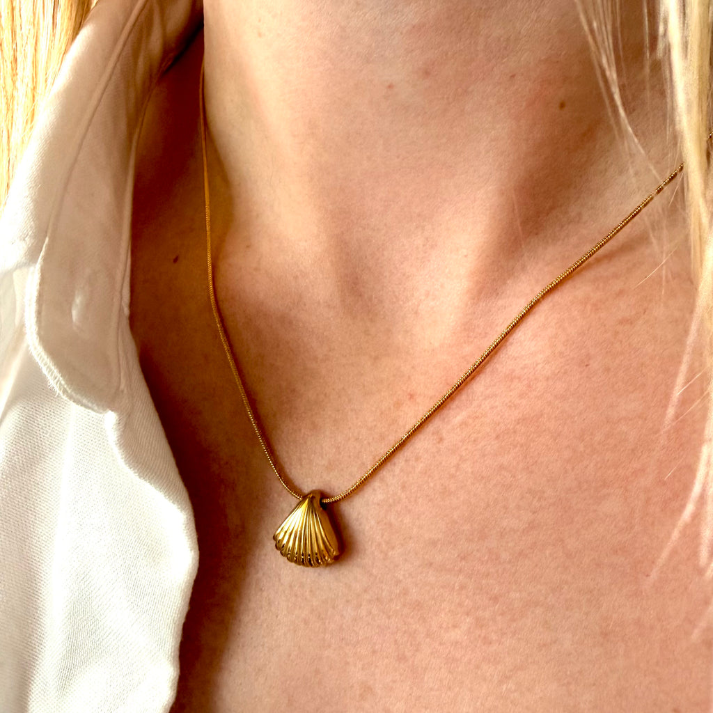 Gold necklace with a shell pendant worn by a woman