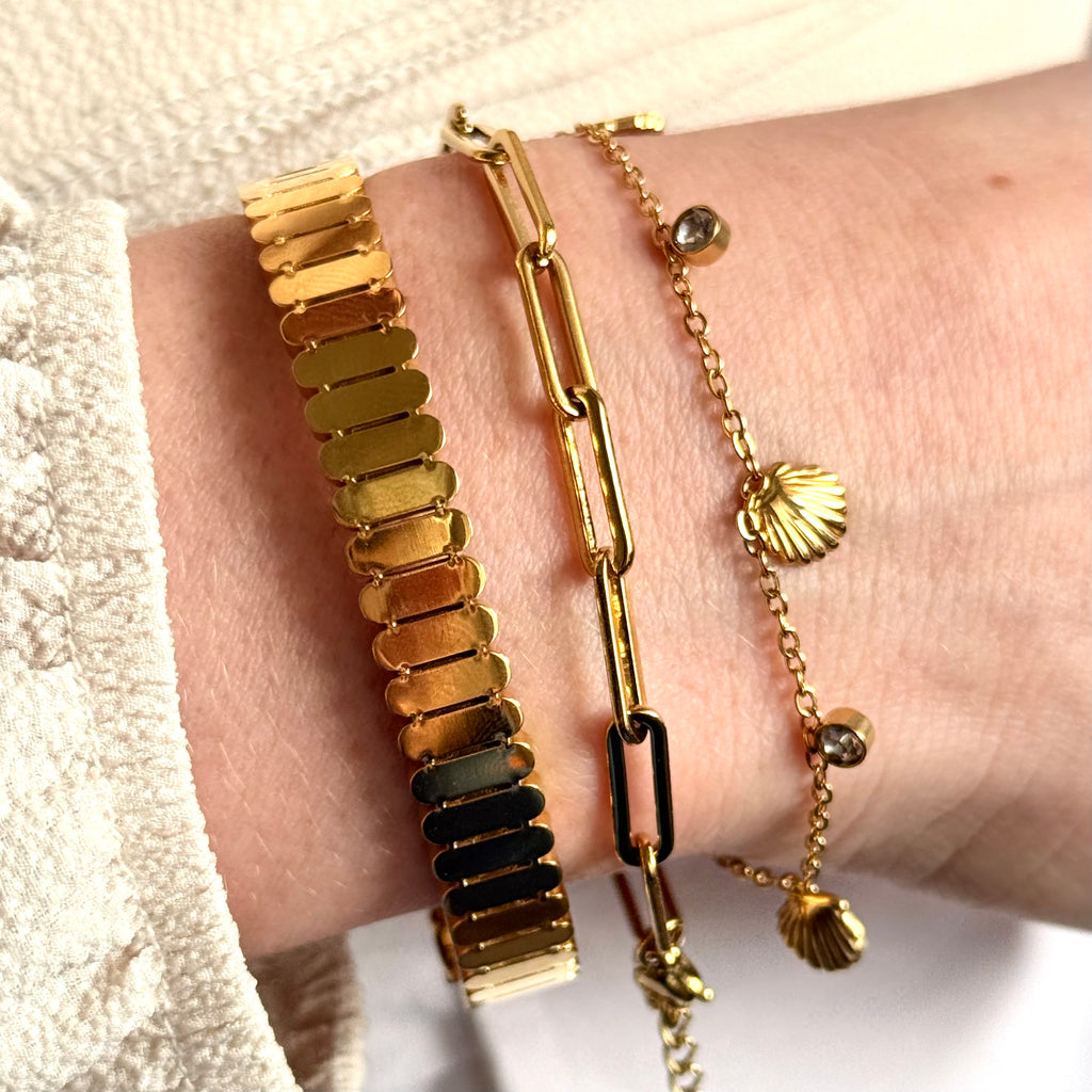 Gold bracelets on a wrist with a neutral background