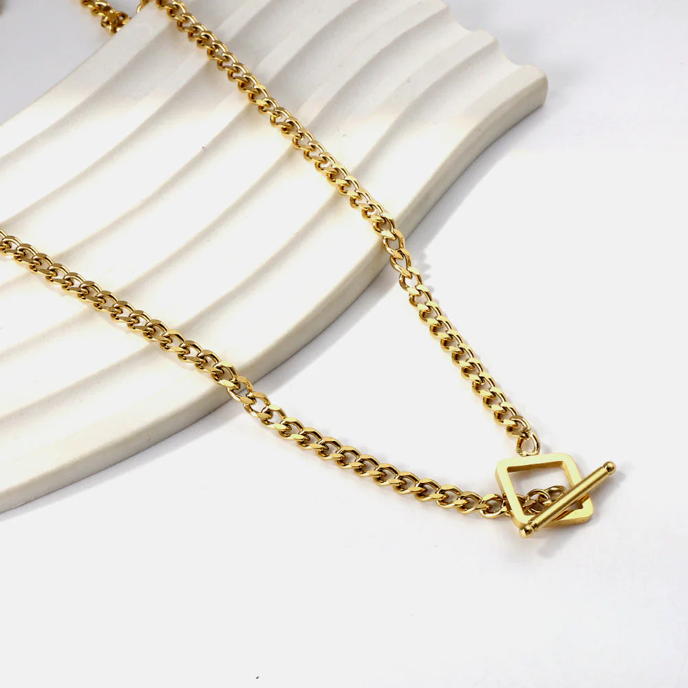 Gold curb chain necklace with a square toggle clasp on a white background