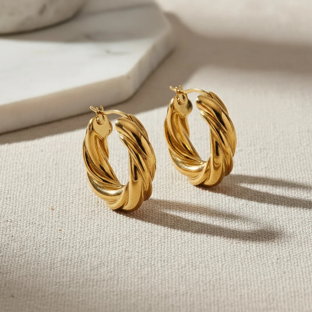 Pair of twisted gold hoop earrings on a white background