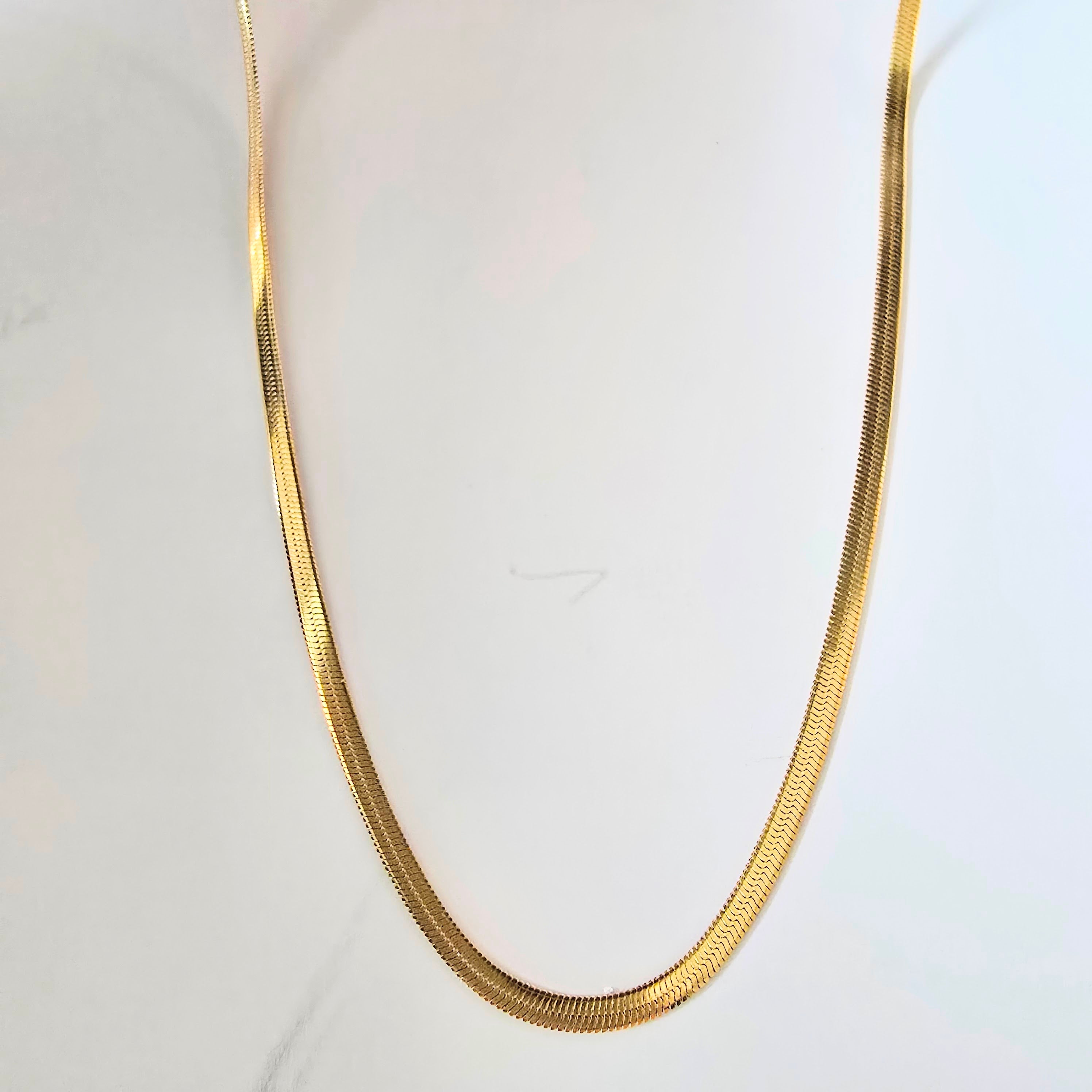 Gold chain necklace on a white background waterproof stainless steel jewelry. gold herringbone necklace, flat chain necklace, minimalist gold necklace