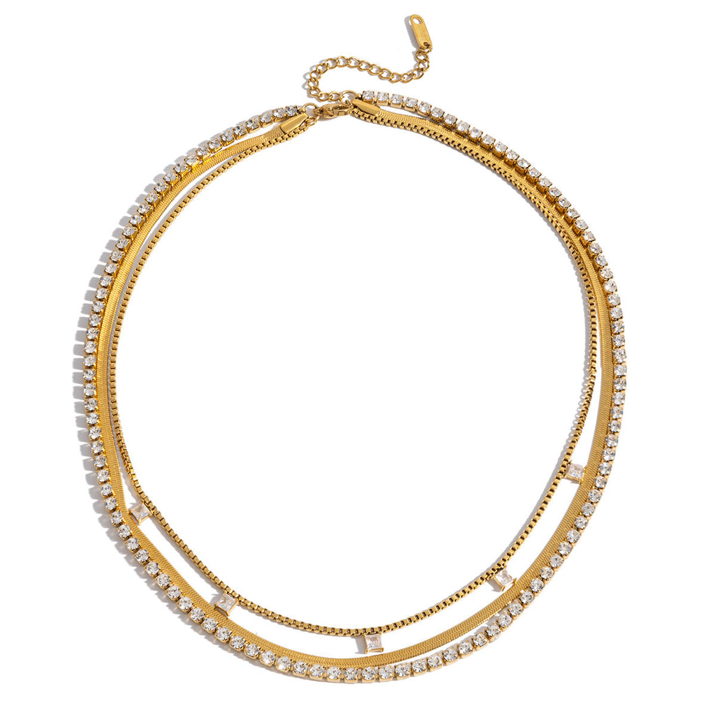 Close-up of a person wearing multiple gold necklaces with cubic zirconia diamonds and herringbone chain necklace. triple layered necklace gold, zirconia layered necklace, gold layering necklace