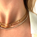 Close-up of a person wearing multiple gold necklaces with cubic zirconia diamonds and herringbone chain necklace. triple layered necklace gold, zirconia layered necklace, gold layering necklace