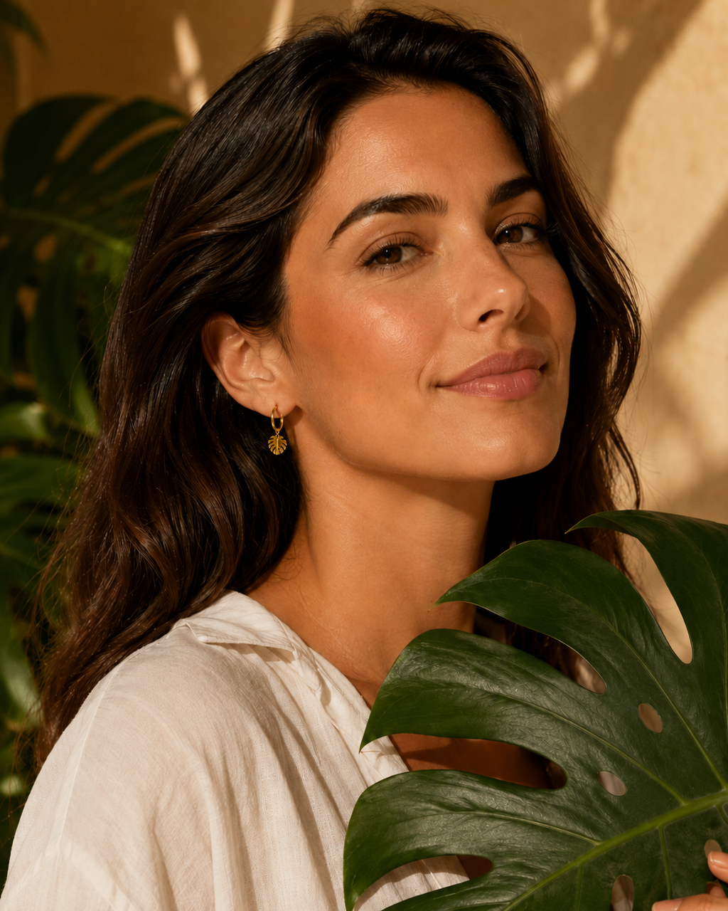 Monsterra drop earring on woman behind monsterra plant