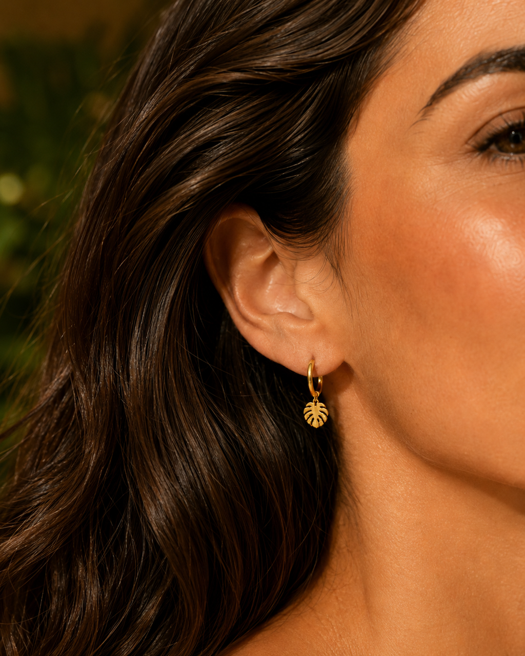 SLose up monsterra leaf drop earring worn by woman