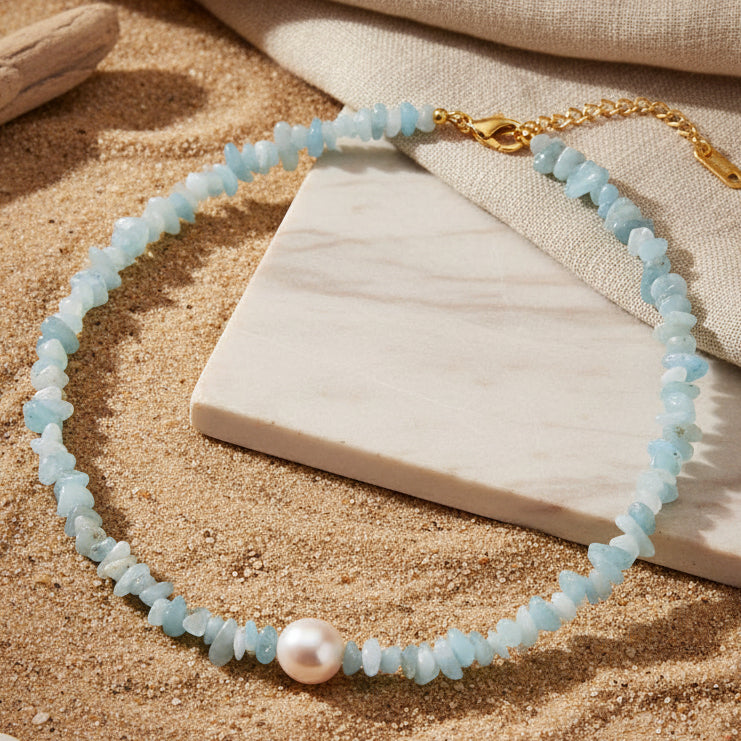 Necklace with natural turquoise irregular stone and a natural pearl laying on sand and marble. natural stone pearl choker, pearl choker necklace gold, beaded choker necklace