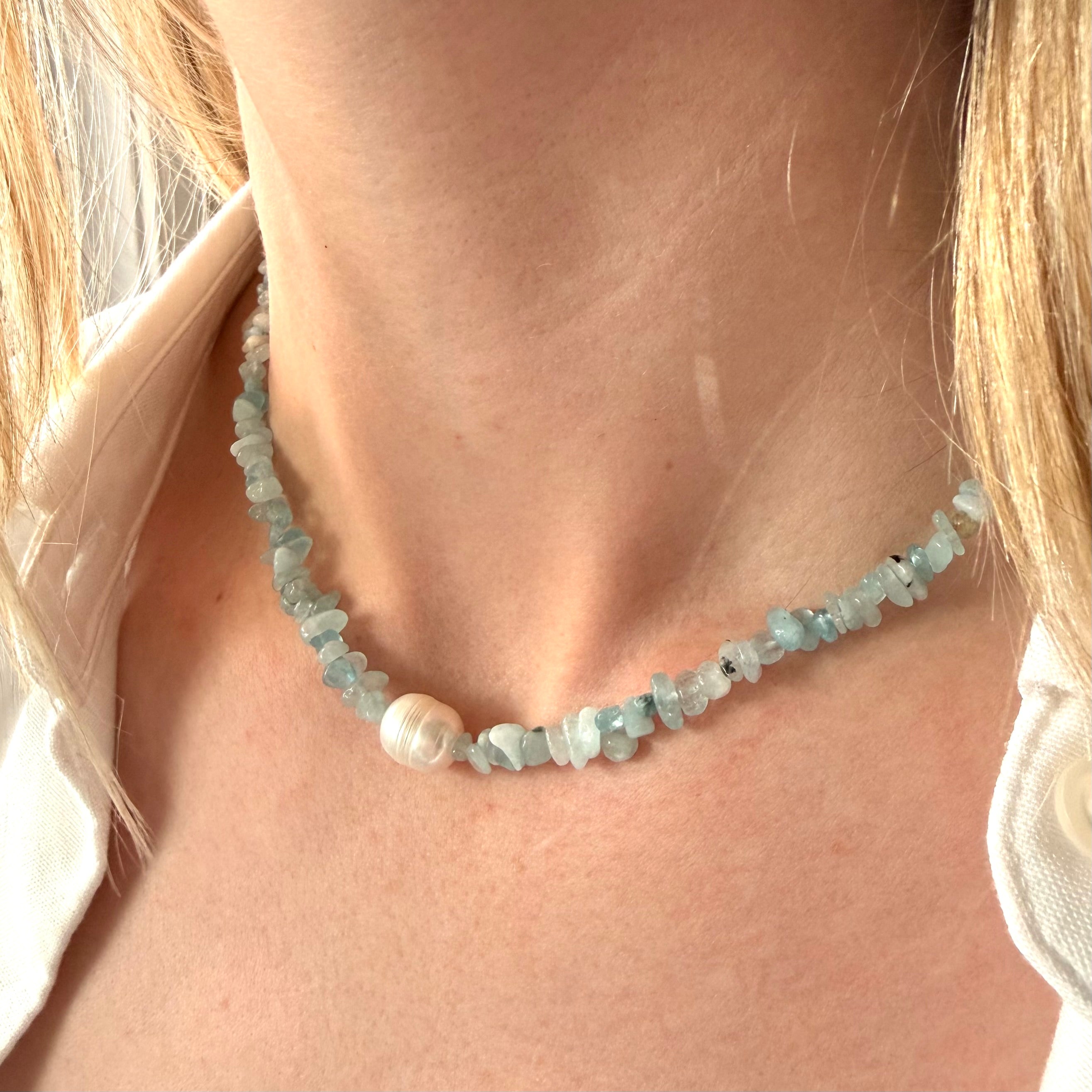 Necklace with natural turquoise irregular stone and a natural pearl laying on sand and marble. natural stone pearl choker, pearl choker necklace gold, beaded choker necklace