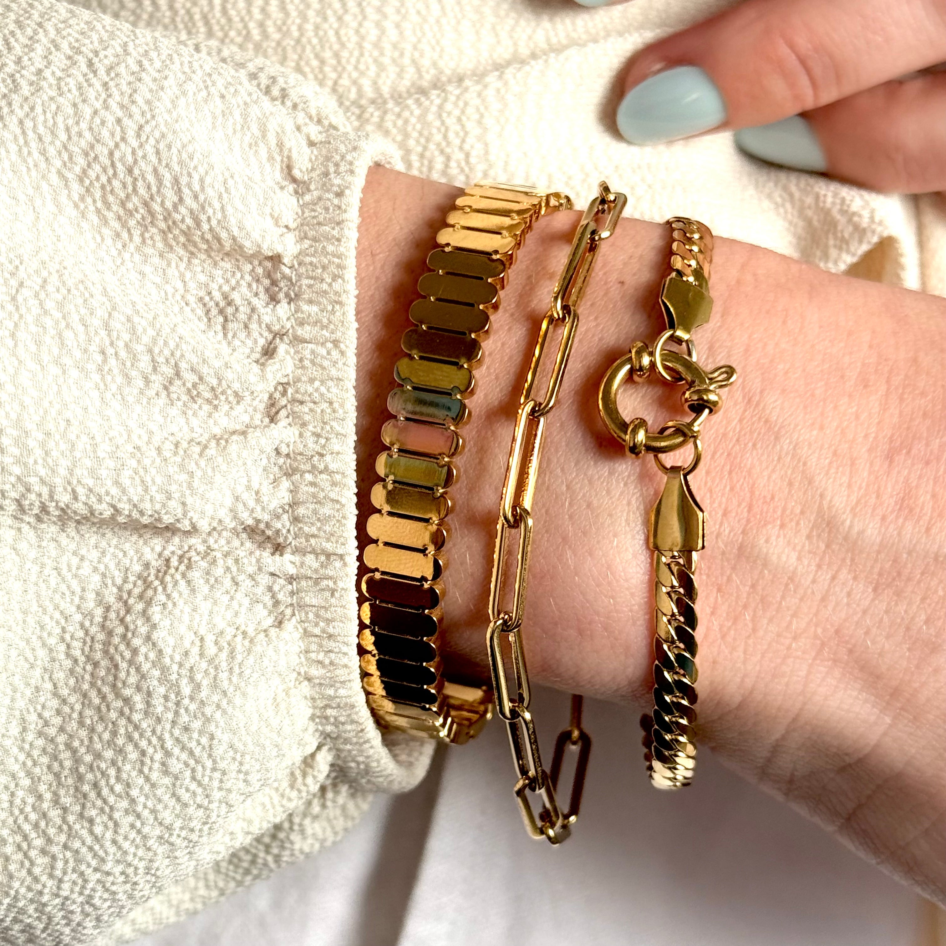 Gold bracelets on a wrist with a neutral background