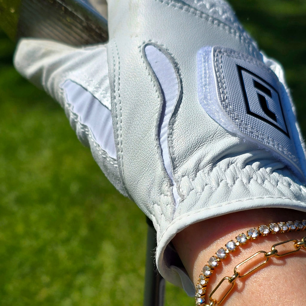 Close-up of a woman wearing a white golf glove with tennis zirconia bracelet