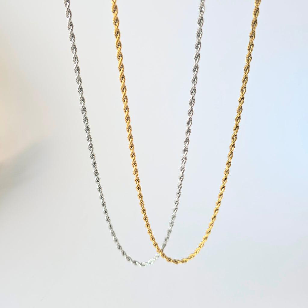 Three gold and silver chains on a light gray background stainless steel waterproof