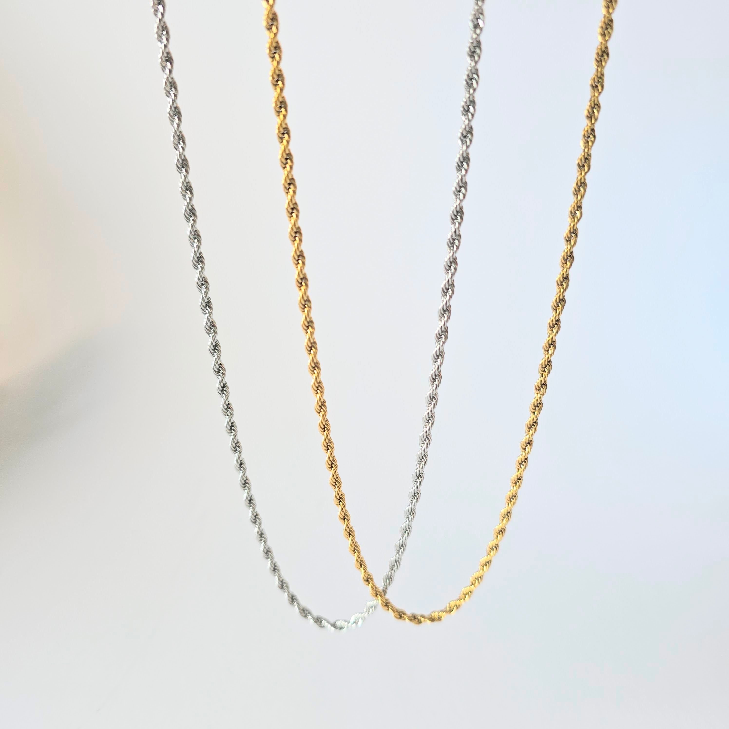 Three gold and silver chains on a light gray background stainless steel waterproof