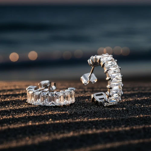 Pair of silver hoop earrings with zirconia gemstones on a white background. Zirconia half hoop earrings, pavé gold earrings, gold half hoop earrings 