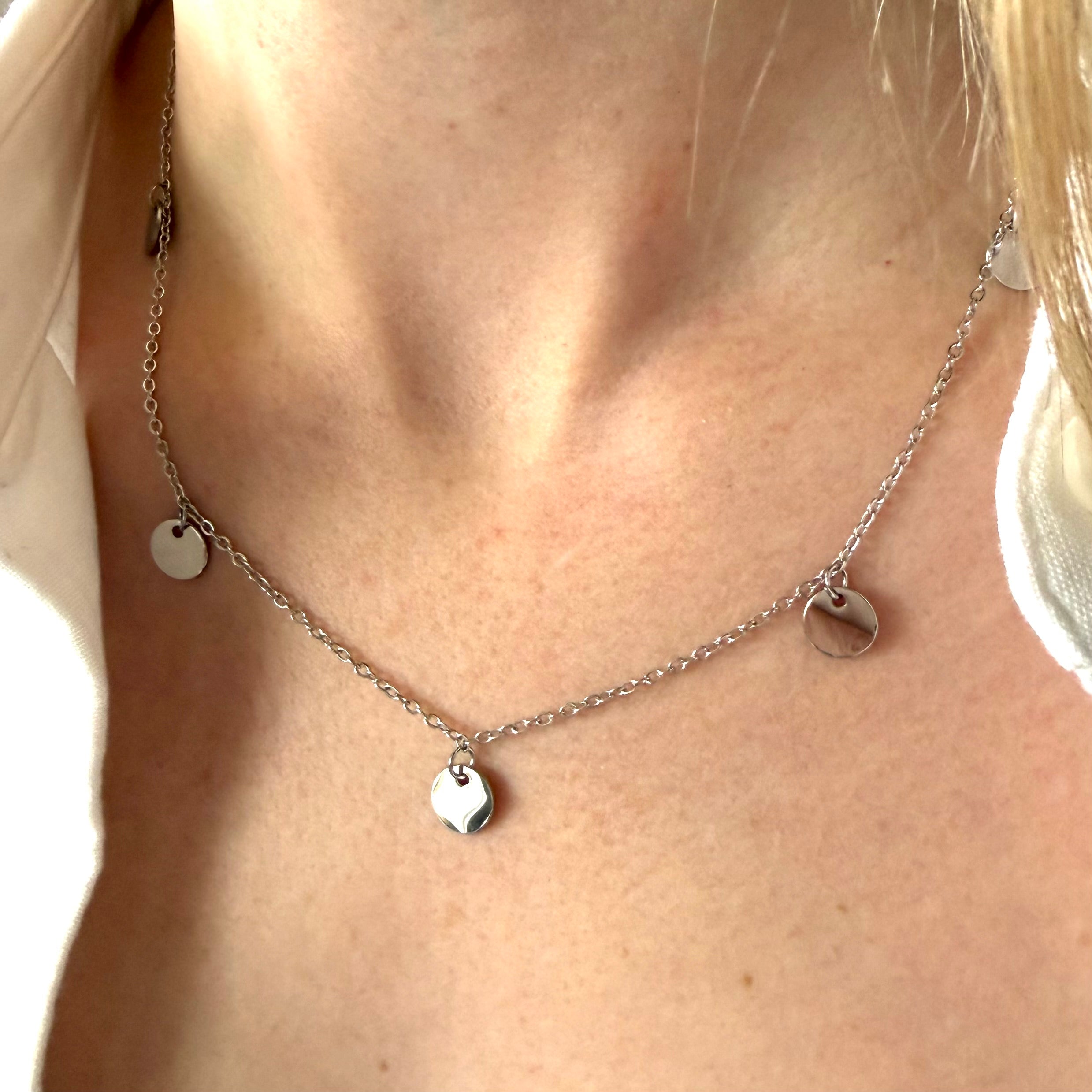 Silver necklace with circle-shaped pendant on a person's neck