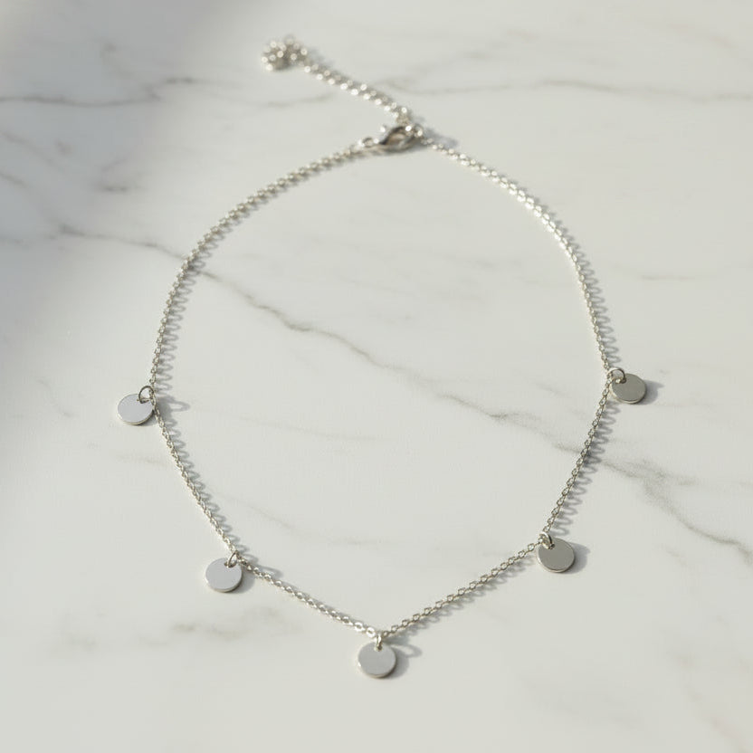 Silver necklace with round pendants on a white background