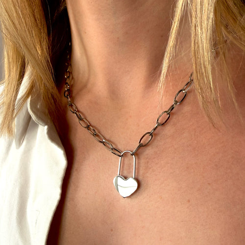 Silver chain necklace with a heart lock pendant on a person.