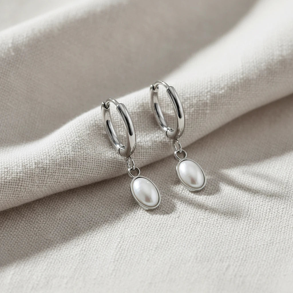 Silver hoop earrings with pearl drops on a white background