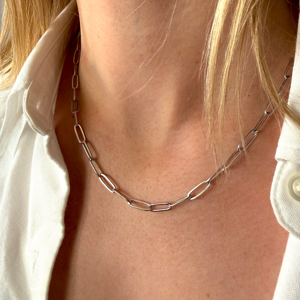 Silver chain paperclip necklace worn by a woman with a white shirt
