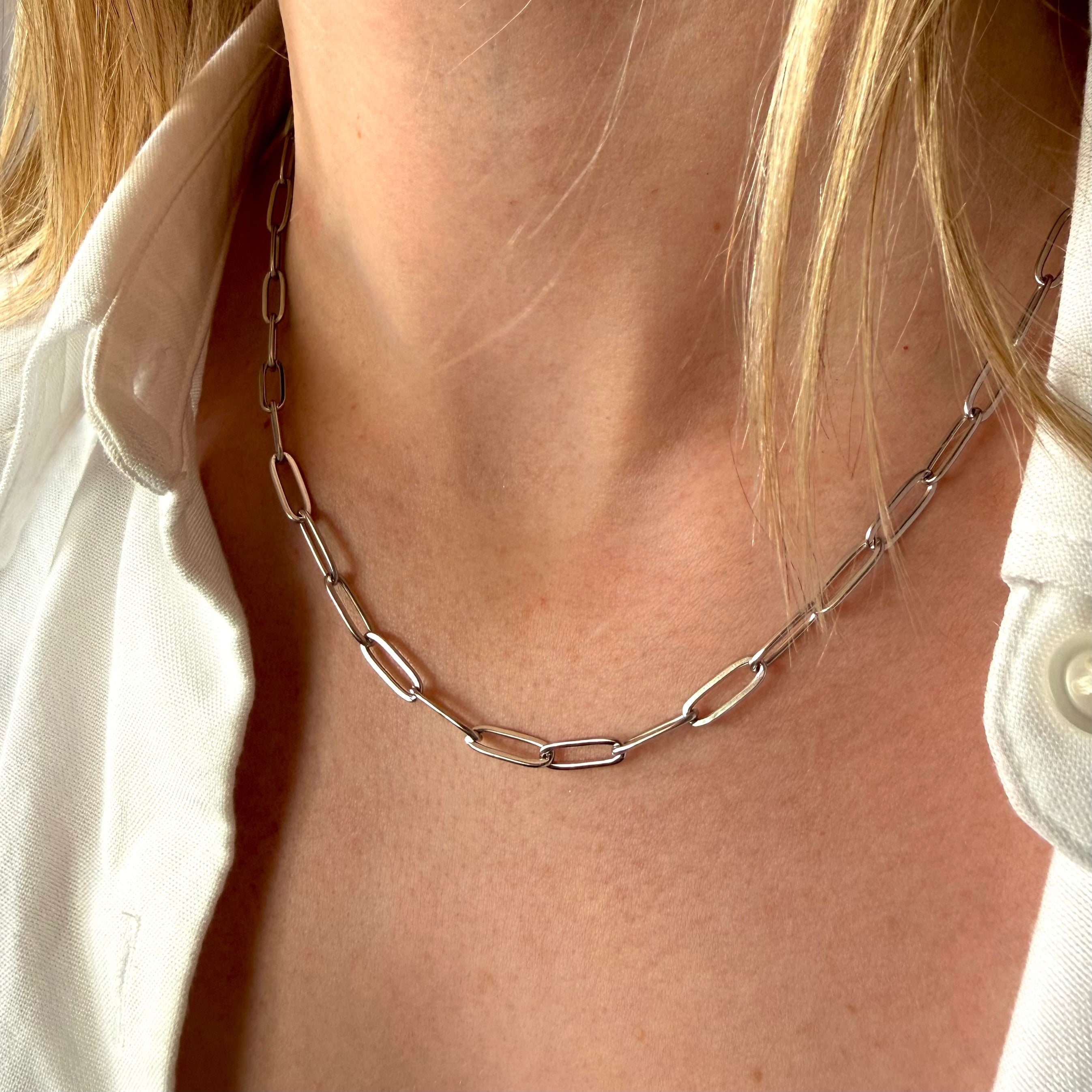 Silver chain paperclip necklace worn by a woman with a white shirt