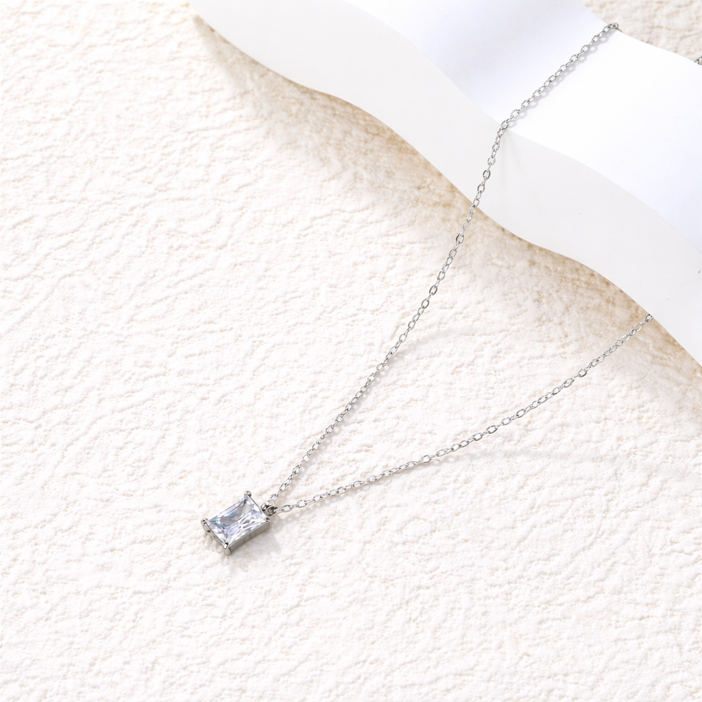 Silver necklace with a square pendant on a textured white surface. rectangular zirconia necklace silver, crystal pendant necklace, minimalist silver necklace